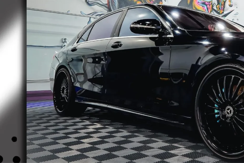 Black Mercedes sedan with glossy finish and custom wheels parked in garage