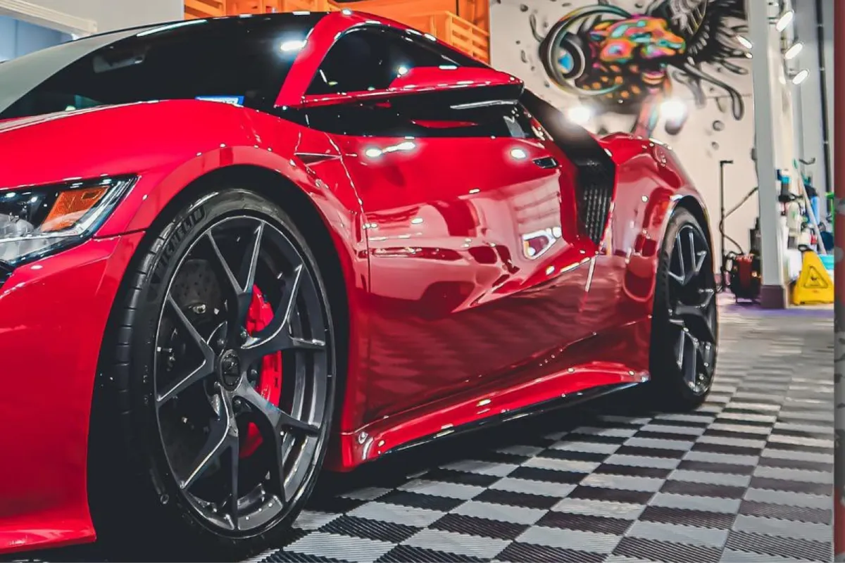 Close-up of a red sports car with sleek design, focused on the wheel