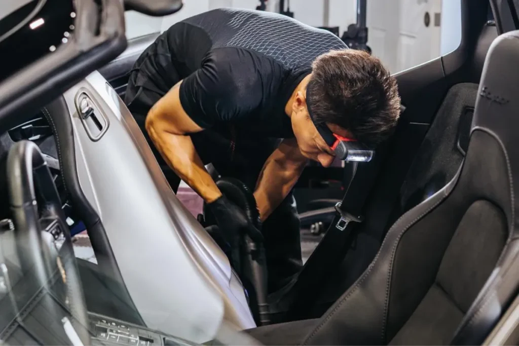 Technician performing interior auto detailing on a luxury car.