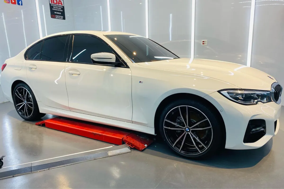 White BMW sedan on lift inside detailing studio