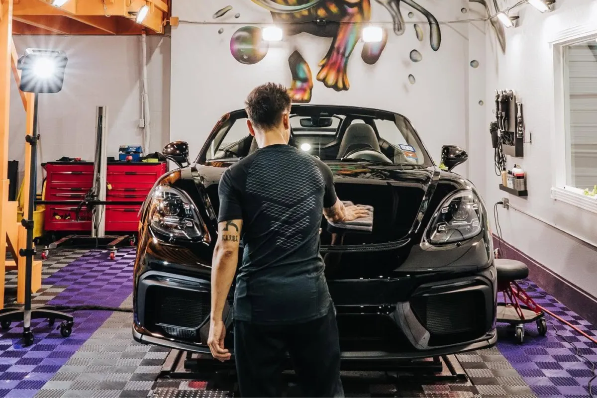 Detailer preparing a black sports car for ceramic coating.