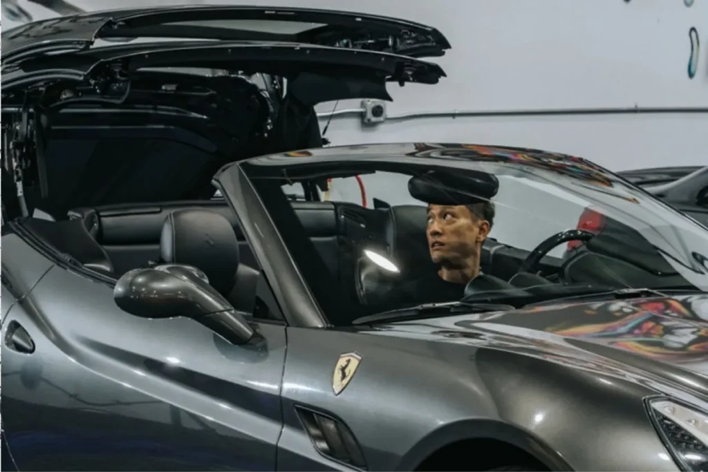 Ferrari convertible with windshield protection film being applied in a detailing shop.